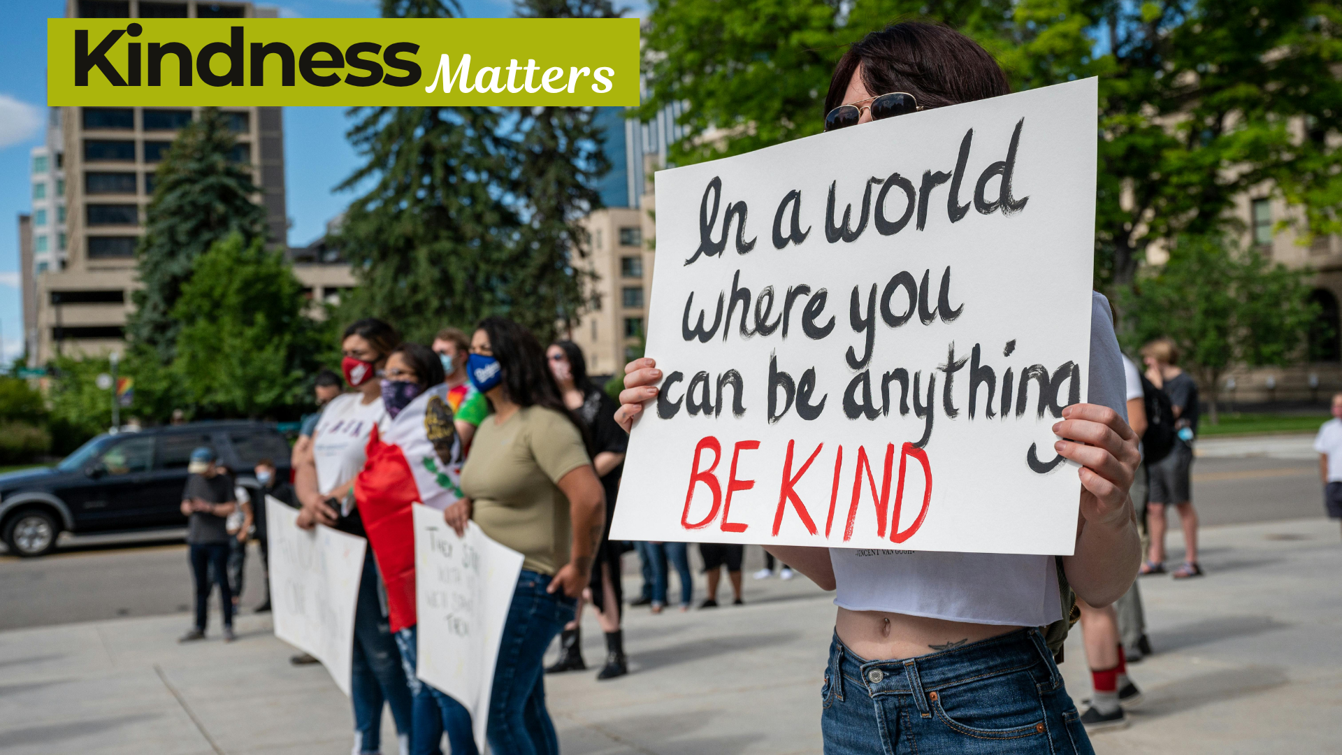 Women's come out from home to road with kindness quote banners in hands on World Kindness Day